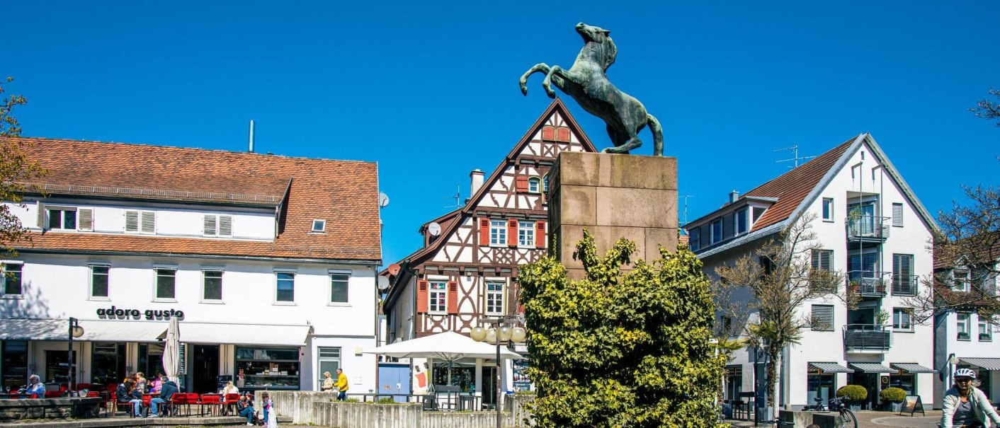 The Rossmarkt in Kirchheim unter Teck shows a horse statue in front of a half-timbered house. People sit in front of a café in sunny weather., © Stuttgart-Marketing GmbH, Sarah Schmid