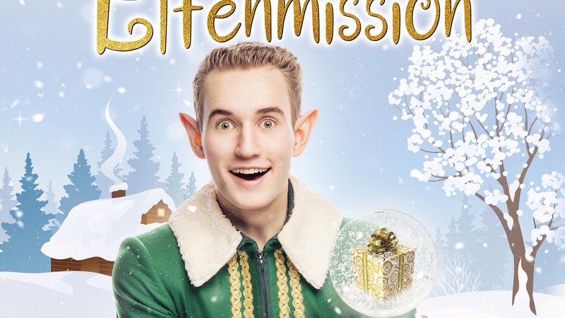 Ein Elf in grünem Kostüm hält eine Schneekugel mit Geschenk. Im Hintergrund eine verschneite Landschaft mit Bäumen und Hütte., © Theaterhaus Stuttgart e.V.