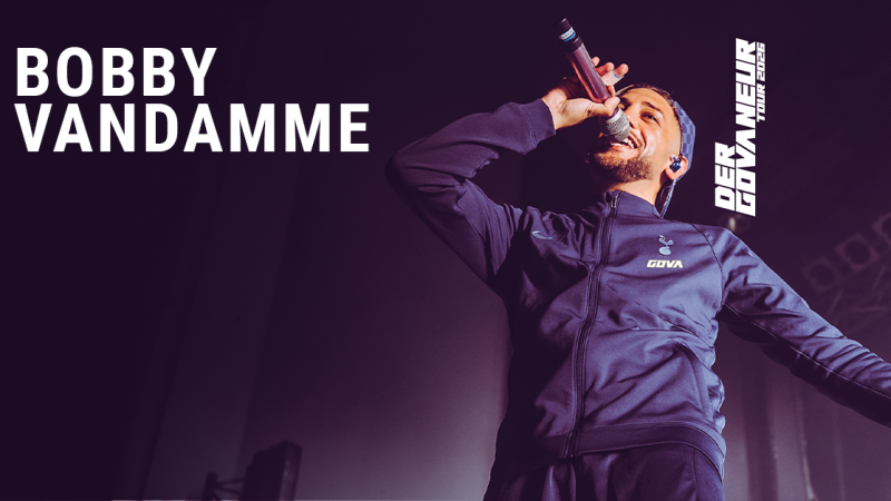 Ein S&auml;nger performt auf der B&uuml;hne in einem dunklen Trainingsanzug. Der Text 'Bobby Vandamme' und 'Der Gouverneur Tour 2026' ist eingeblendet., &copy; links im Bild
