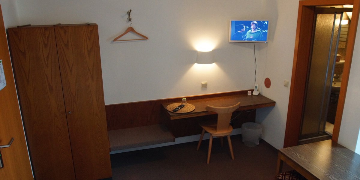 Ein einfach eingerichtetes Einzelzimmer mit Schreibtisch, Stuhl, Fernseher an der Wand, Kleiderschrank und einem angrenzenden Badezimmer., © Hotelmärchen Ein einfach eingerichtetes Einzelzimmer mit Schreibtisch, Stuhl, Fernseher an der Wand, Kleiderschrank und einem angrenzenden Badezimmer., © Hotelmärchen