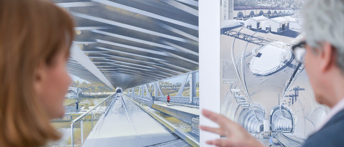 Zwei Personen betrachten detaillierte Architekturzeichnungen in einer Galerie. Die Bilder zeigen futuristische Tunnel- und Brückenkonstruktionen., © GALERIE Z Zwei Personen betrachten detaillierte Architekturzeichnungen in einer Galerie. Die Bilder zeigen futuristische Tunnel- und Brückenkonstruktionen., © GALERIE Z