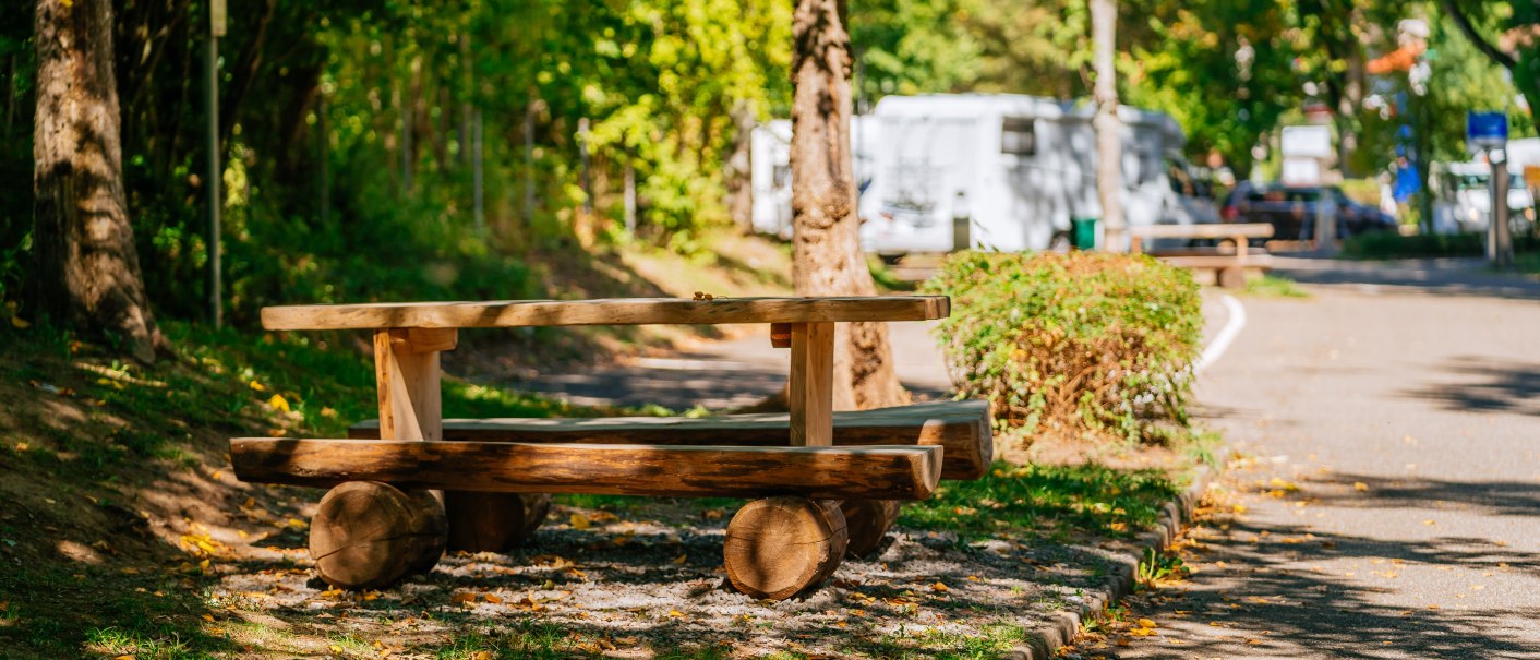 A wooden table stands on a camper van site in Bad Wildbad, surrounded by trees and a camper van in the background., &copy; Stuttgart-Marketing GmbH, Thomas Niederm&uuml;ller