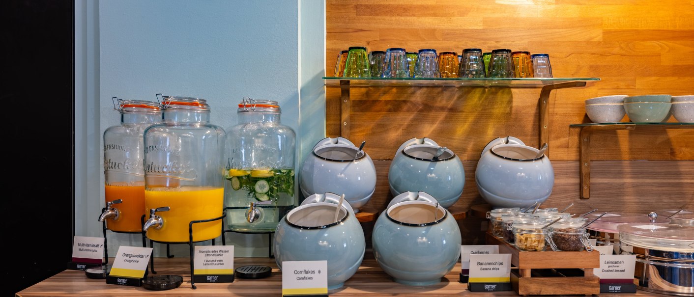 A breakfast buffet with juice dispensers, cereal bowls, and glasses. A variety of juices and cereals are available to choose from., &copy; Novum  Hospitality