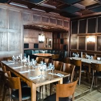 Elegant restaurant with wooden walls, laid tables and candlelight. Dark wooden furniture and a cozy atmosphere dominate the room., © Weinstube Fröhlich Verwaltungs GmbH