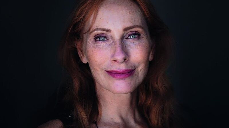 Eine Frau mit roten Haaren und einem glitzernden Oberteil lächelt vor einem dunklen Hintergrund., © MSK Events GmbH Eine Frau mit roten Haaren und einem glitzernden Oberteil lächelt vor einem dunklen Hintergrund., © MSK Events GmbH