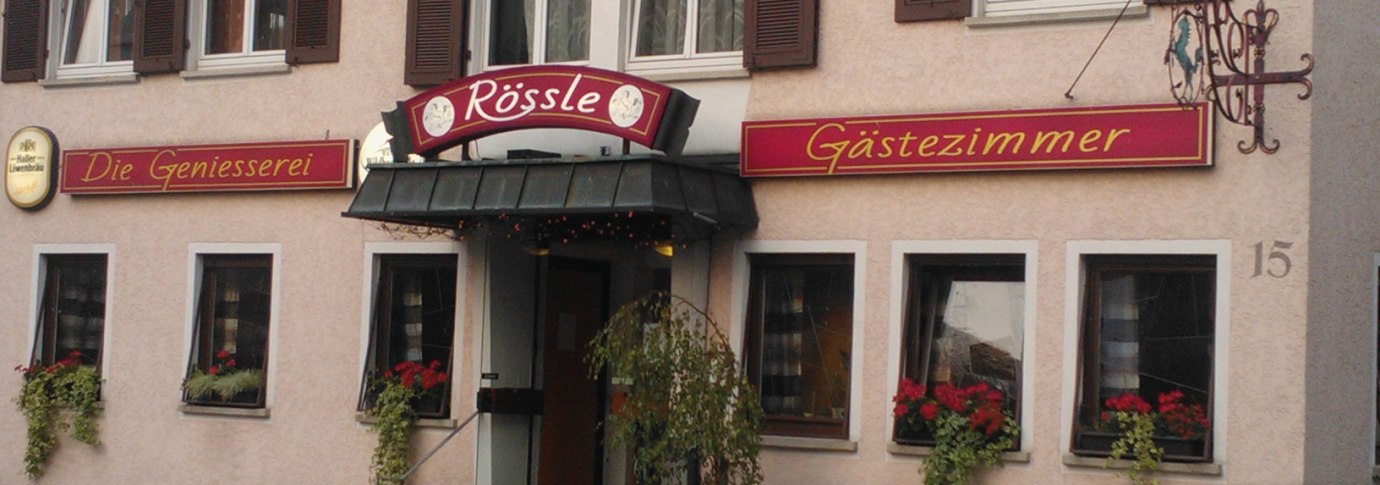 Gasthaus Rössle in Urbach mit Schildern 'Die Geniesserei' und 'Gästezimmer', Blumenkästen an den Fenstern und einer Eingangstreppe., © Gasthaus Rössle