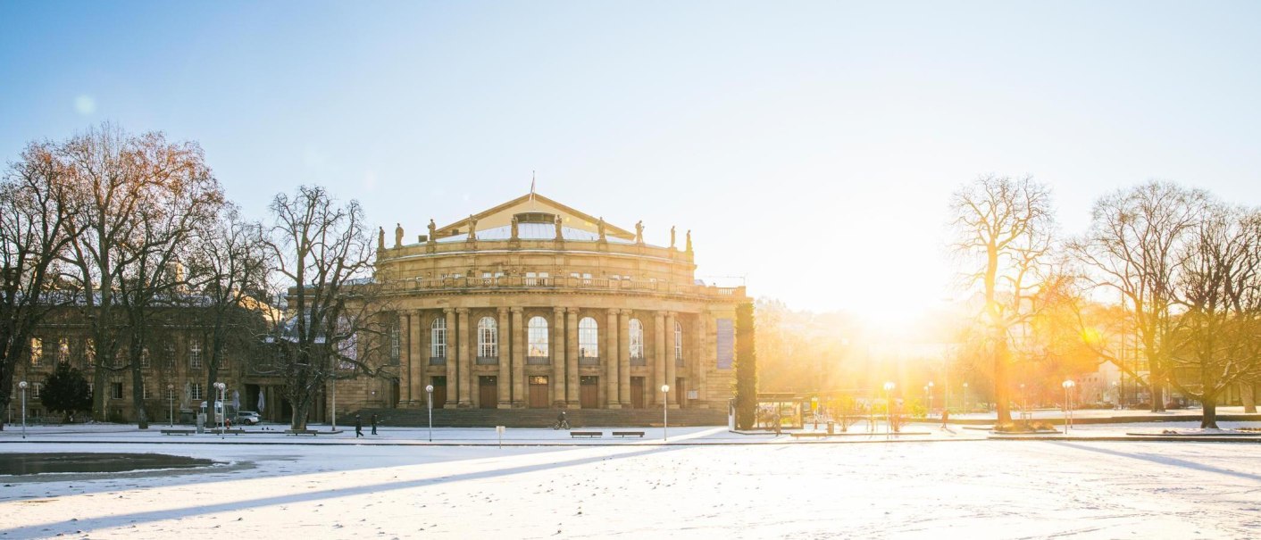 Die Stuttgarter Staatsoper im Winter, umgeben von schneebedecktem Boden und kahlen B&auml;umen. Die Sonne geht im Hintergrund auf und taucht die Szene in warmes Licht., &copy; Stuttgart-Marketing GmbH, Sarah Schmid