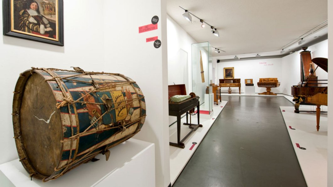 Museumsausstellung mit historischen Musikinstrumenten, darunter eine bemalte Trommel im Vordergrund und verschiedene Tasteninstrumente im Hintergrund., © Landesmuseum Württemberg Museumsausstellung mit historischen Musikinstrumenten, darunter eine bemalte Trommel im Vordergrund und verschiedene Tasteninstrumente im Hintergrund., © Landesmuseum Württemberg