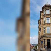 Historisches Eckgebäude mit Apotheke im Erdgeschoss, umgeben von Straßen und Autos, unter blauem Himmel., © SMG Historisches Eckgebäude mit Apotheke im Erdgeschoss, umgeben von Straßen und Autos, unter blauem Himmel., © SMG