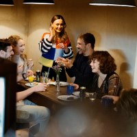 A group of people are sitting around a table in a café and laughing. A woman stands and talks to the others. The atmosphere is cozy., © Stuttgart Marketing, Alwin Maigler A group of people are sitting around a table in a café and laughing. A woman stands and talks to the others. The atmosphere is cozy., © Stuttgart Marketing, Alwin Maigler