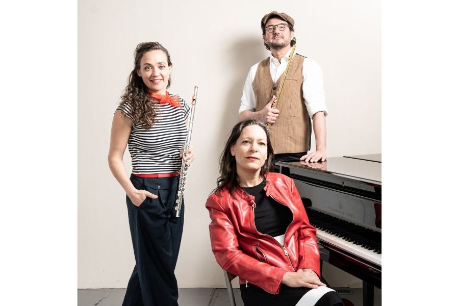 Drei Musiker posieren vor einem Klavier. Zwei halten Fl&ouml;ten, eine Person sitzt am Klavier. Sie tragen stilvolle, farbenfrohe Kleidung., &copy; Trio Funkenflug