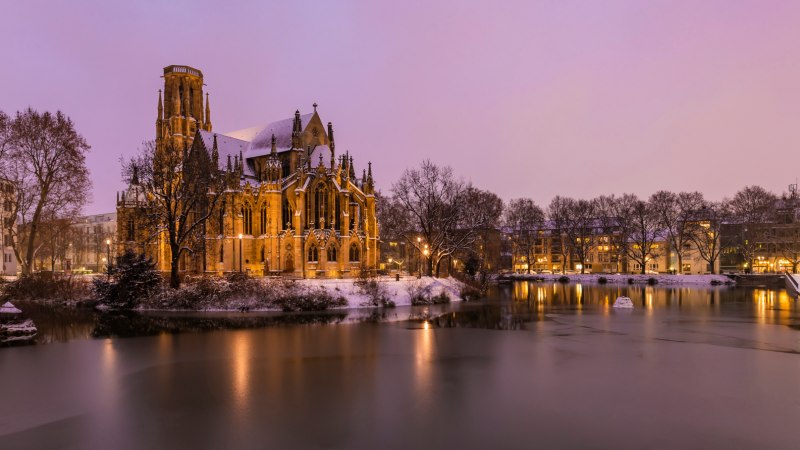 Die Johanneskirche am Feuersee in winterlicher Abendstimmung, umgeben von Schnee und beleuchtetem Wasser., © Werner Dietrich Die Johanneskirche am Feuersee in winterlicher Abendstimmung, umgeben von Schnee und beleuchtetem Wasser., © Werner Dietrich