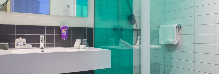 Modern bathroom with glass shower, white washbasin and large mirror. Black and white tiles dominate the design., © Park Inn by Radisson Stuttgart Modern bathroom with glass shower, white washbasin and large mirror. Black and white tiles dominate the design., © Park Inn by Radisson Stuttgart