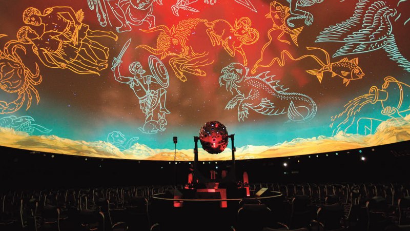 Innenansicht eines Planetariums mit leeren Sitzen und projizierten Sternbildern an der Kuppel. Ein Projektor steht in der Mitte., © Planetarium Stuttgart Innenansicht eines Planetariums mit leeren Sitzen und projizierten Sternbildern an der Kuppel. Ein Projektor steht in der Mitte., © Planetarium Stuttgart