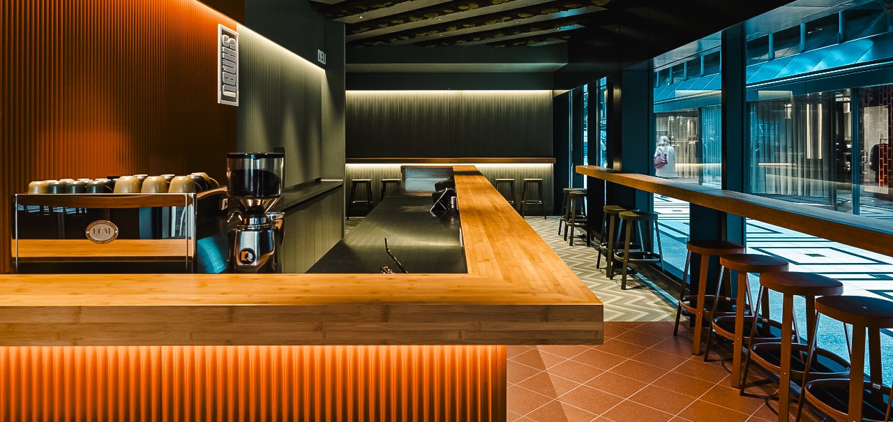 Moderne Bar mit Holztresen, Hockern und stilvoller Beleuchtung in der Shobu Calwer Passage. Dunkle W&auml;nde und geometrische Deckenmuster., &copy; Blackbook Studios