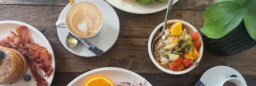 A richly laid breakfast table with coffee, pancakes with bacon, avocado with scrambled eggs and a bowl of fresh fruit., &copy; SMG