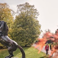 Bronze statue of an ascending horse in the Höhenpark Killesberg, surrounded by autumnal trees and a spiral-shaped observation tower in the background., © SMG, Christoph Düpper