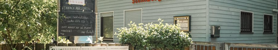 The NaturFreundeHaus Steinbergle with a sign announcing live jazz, surrounded by plants and a wooden fence., &copy; NaturFreundehaus Steinbergle, Stuttgart