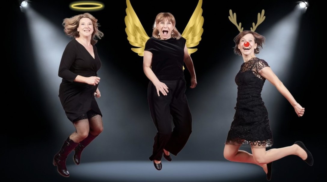 Three women in black outfits jump on a stage. One has a halo, one has angel wings and the third has reindeer antlers with a red nose., &copy; Improtheater Stuttgart / Rainer Wengel Fotografie