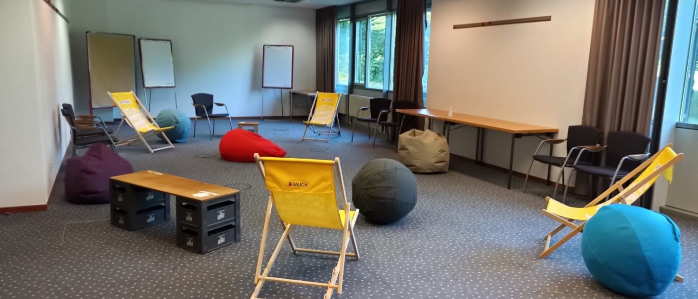 Ein Tagungsraum mit Liegestühlen, bunten Sitzsäcken und Flipcharts. Der Raum hat Teppichboden und große Fenster mit Vorhängen., © Seminaris Hotel Bad Boll