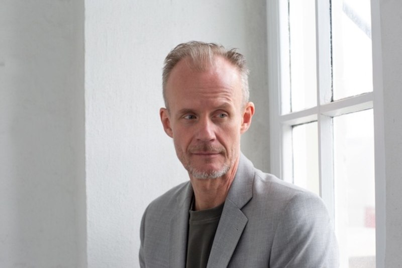 A man leans relaxed against a wall and looks confidently into the camera. He has a light beard and short hair., &copy; Renitenztheater Stuttgart e.V.