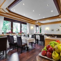 Elegant breakfast room with laid tables, dark chairs and a fruit bowl in the foreground. Large windows let in plenty of light., © ARNOTEL GmbH Elegant breakfast room with laid tables, dark chairs and a fruit bowl in the foreground. Large windows let in plenty of light., © ARNOTEL GmbH
