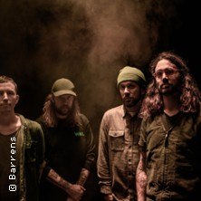 Vier M&auml;nner posieren in einem nebligen Raum, gekleidet in dunklen, l&auml;ssigen Outfits. Die Stimmung ist ernst und geheimnisvoll., &copy; links im Bild