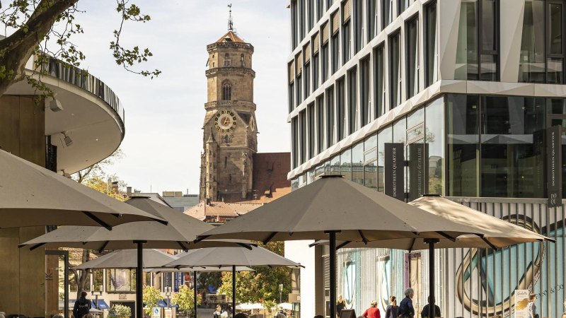 Das Dorotheenquartier in Stuttgart mit modernen Gebäuden, Sonnenschirmen und der historischen Stiftskirche im Hintergrund., © Stuttgart-Marketing GmbH, Sarah Schmid