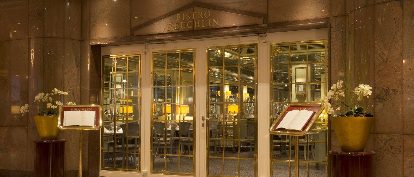Eleganter Eingang des Bistro Reuchlin mit goldenen Türen, Menükartenständern und dekorativen Pflanzen., © Maritim Hotelgesellschaft mbH Eleganter Eingang des Bistro Reuchlin mit goldenen Türen, Menükartenständern und dekorativen Pflanzen., © Maritim Hotelgesellschaft mbH