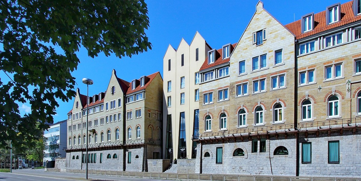 Das Arcotel Camino Stuttgart zeigt eine moderne Fassade mit traditionellen Elementen unter blauem Himmel, umgeben von Bäumen., © Arcotel Hotels