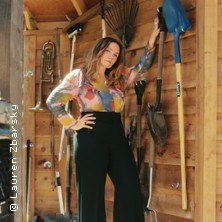 Person in bunter Bluse steht in einem Schuppen, umgeben von Gartengeräten an der Wand., © links im Bild Person in bunter Bluse steht in einem Schuppen, umgeben von Gartengeräten an der Wand., © links im Bild