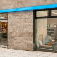 Gro&szlig;e Fensterfronten, die Blick auf das Caf&eacute; im Inneren freigeben: Holztische, wei&szlig;e Kissen., &copy; Stuttgart-Marketing GmbH, Sarah Schmid