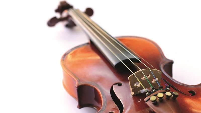 Nahaufnahme einer Violine, die auf einem wei&szlig;en Hintergrund liegt. Die Saiten und der Korpus sind deutlich sichtbar., &copy; Shutterstock