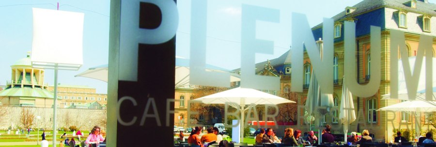 People sit under parasols in the outdoor area of a café. Historical buildings can be seen in the background., © SMG People sit under parasols in the outdoor area of a café. Historical buildings can be seen in the background., © SMG