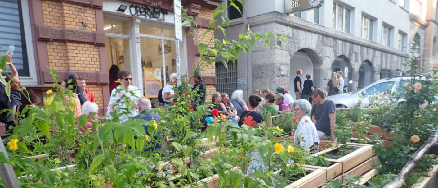 Menschen genie&szlig;en einen urbanen Garten vor einem Geb&auml;ude mit der Aufschrift 'Oberwelt'. Es herrscht eine entspannte Atmosph&auml;re., &copy; Oberwelt e.V.