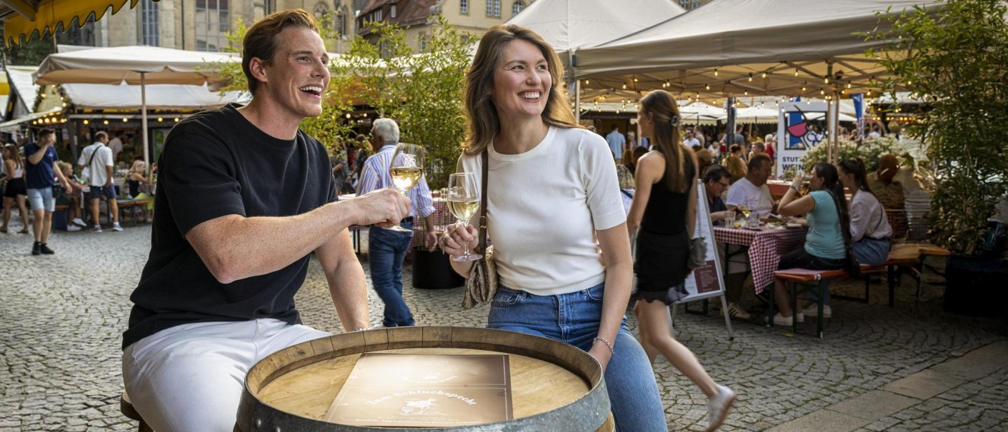 Zwei Personen stoßen mit Weingläsern auf dem Stuttgarter Weindorf an. Im Hintergrund sind Stände und Besucher zu sehen., © Stuttgart-Marketing GmbH, Sarah Schmid Zwei Personen stoßen mit Weingläsern auf dem Stuttgarter Weindorf an. Im Hintergrund sind Stände und Besucher zu sehen., © Stuttgart-Marketing GmbH, Sarah Schmid