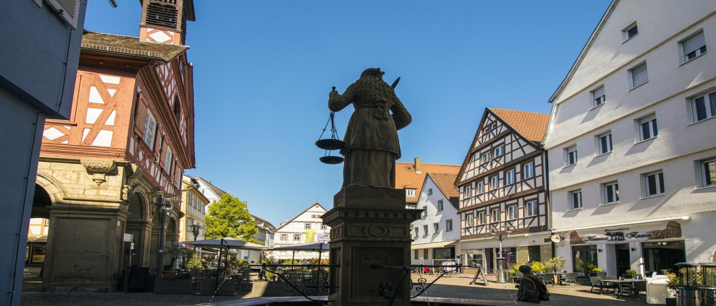 The market square in Waiblingen shows half-timbered houses and a statue in the foreground. The sky is clear and blue., © SMG Stuttgart Marketing GmbH - Sarah Schmid