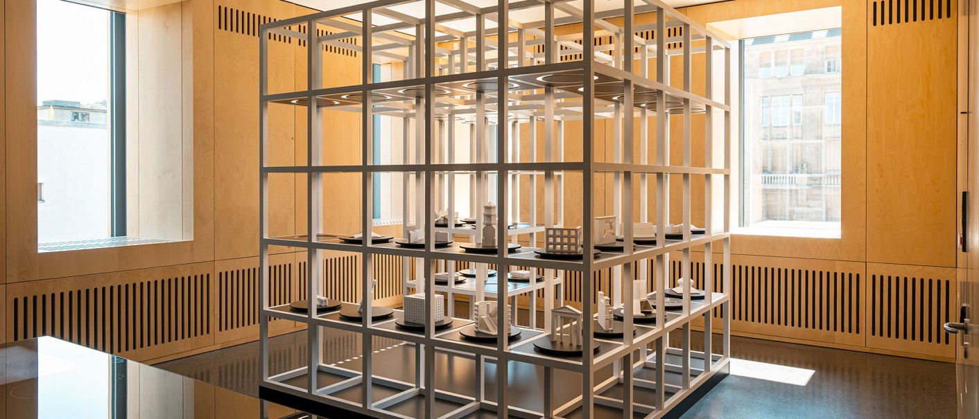 Ein heller Raum mit einem großen, weißen Gitterregal, das kleine Architekturmodelle präsentiert. Holzwände und große Fenster sorgen für viel Licht., © Stuttgart Marketing GmbH, Sarah Schmid