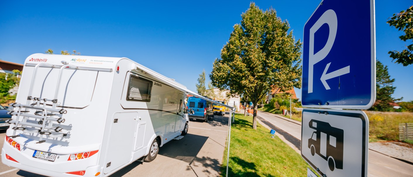 Wohnmobilstellplatz mit mehreren Wohnmobilen und Parkschildern. Ein Baum und blauer Himmel im Hintergrund., &copy; Stuttgart-Marketing GmbH, Thomas Niederm&uuml;ller
