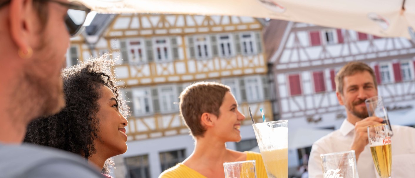 People sit at a table on Herrenberg's market square and enjoy drinks. Half-timbered houses can be seen in the background., © Stuttgart-Marketing GmbH, Martina Denker
