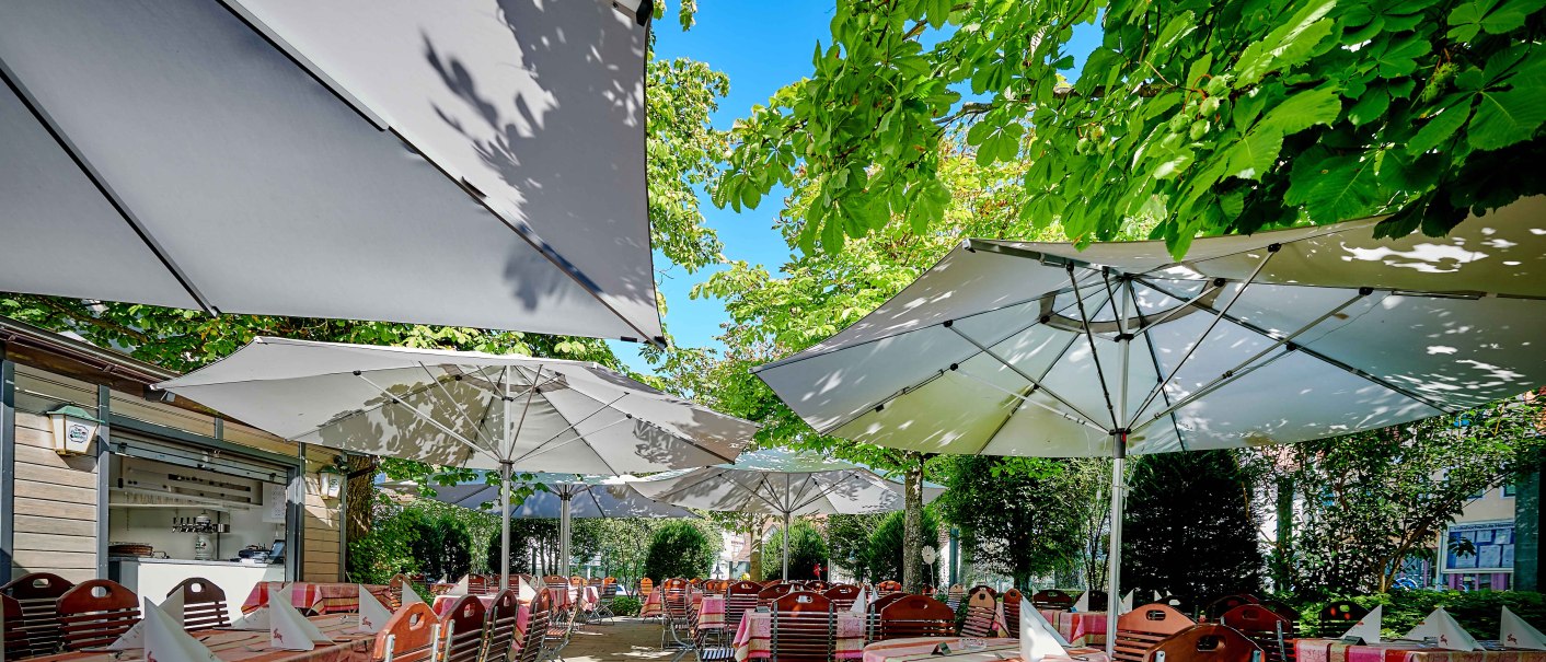 Garden terrace with covered tables under large parasols, surrounded by lush greenery and trees., © Hotel Gasthof Hasen Garden terrace with covered tables under large parasols, surrounded by lush greenery and trees., © Hotel Gasthof Hasen