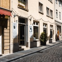 A sunny alleyway with cobblestones, lined with stores such as a second-hand bookshop. Fairy lights hang above the entrances., &copy; SMG Stuttgart Marketing GmbH - Sarah Schmid