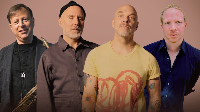 Vier Männer posieren vor einem braunen Hintergrund. Einer hält ein Saxophon, die anderen tragen lässige Kleidung. Sie blicken in verschiedene Richtungen., © Theaterhaus Stuttgart e.V. Vier Männer posieren vor einem braunen Hintergrund. Einer hält ein Saxophon, die anderen tragen lässige Kleidung. Sie blicken in verschiedene Richtungen., © Theaterhaus Stuttgart e.V.