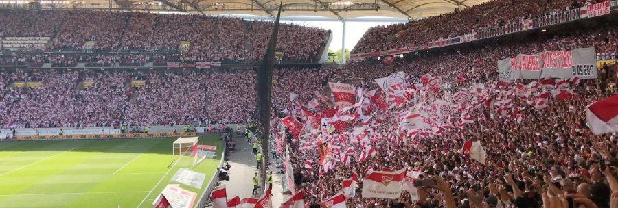 Blick in die Cannstatter Kurve der Mercedes-Benz Arena Stuttgart. Fans schwenken rot-wei&szlig;e Fahnen und halten Banner hoch. Die Trib&uuml;nen sind voll besetzt., &copy; Stuttgart-Marketing GmbH