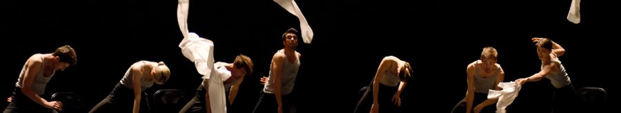 Dancers on a dark stage throw white scarves into the air. They wear black clothes and move in sync., &copy; Regina Brocke