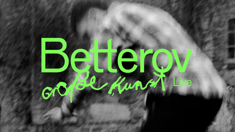 Schwarz-weiß Bild mit verschwommenem Hintergrund und grünem Text 'Betterov große Kunst Live'., © links im Bild Schwarz-weiß Bild mit verschwommenem Hintergrund und grünem Text 'Betterov große Kunst Live'., © links im Bild