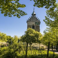 A church tower in Fellbach rises up between green trees under a clear blue sky. The surroundings are peaceful and inviting., © SMG Stuttgart Marketing GmbH - Sarah Schmid