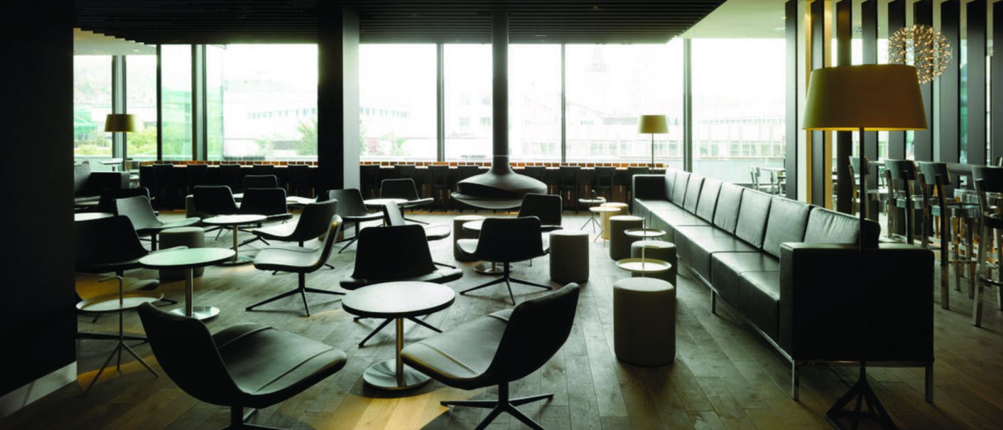 Moderne Lounge mit schwarzen Ledersesseln, Tischen und Stehlampen. Gro&szlig;e Fenster bieten Blick nach drau&szlig;en. Elegantes, minimalistisches Design., &copy; karls kitchen, Stuttgart