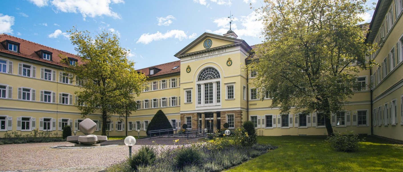 The Kurhaus Bad Boll has a yellow facade with many windows. In the foreground, you can see a tree and a well-tended garden., © SMG Stuttgart Marketing GmbH - Sarah Schmid The Kurhaus Bad Boll has a yellow facade with many windows. In the foreground, you can see a tree and a well-tended garden., © SMG Stuttgart Marketing GmbH - Sarah Schmid