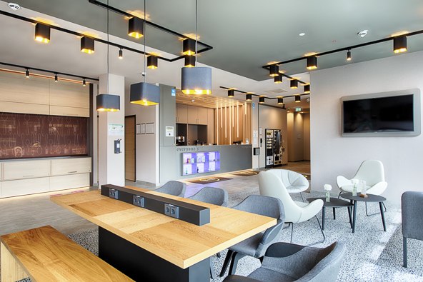 Moderne Lobby mit stilvollen Sitzgelegenheiten, Holztisch, Deckenbeleuchtung und einem gro&szlig;en Bildschirm an der Wand., &copy; B&B Hotel Stuttgart-Neckarhafen